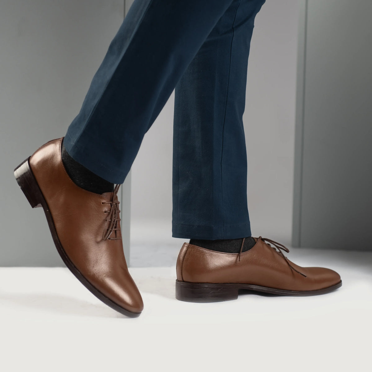 Perspectiva del modelo vistiendo Director Wholecut Tostado Zapatos de cuero para Hombre en modelo con caída natural bajo luz de día